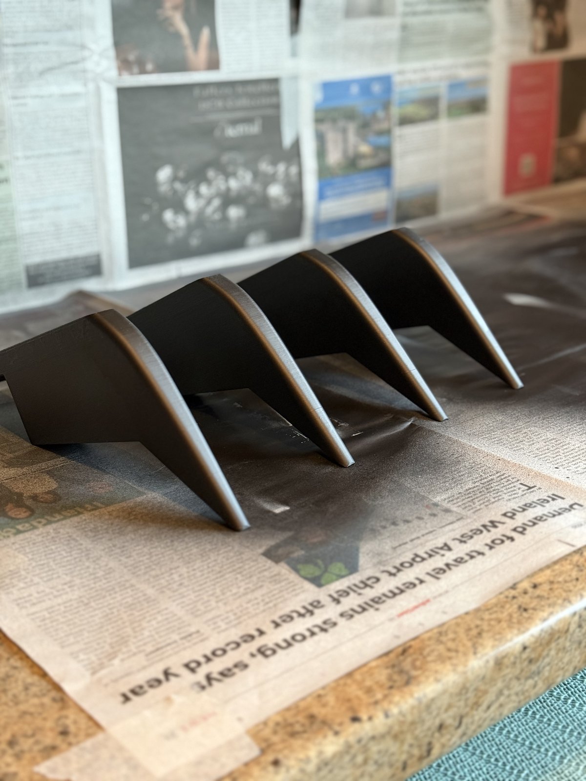 A matte black four-fin rear diffuser for a Skoda Octavia vRS Mk3, laid out on newspaper before fitting